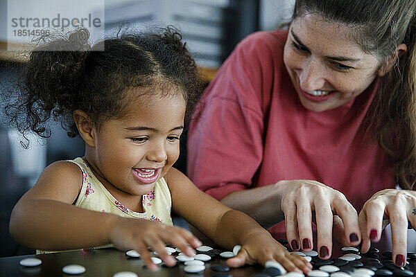 Glückliche Mutter und Tochter spielen zu Hause Go-Spiel
