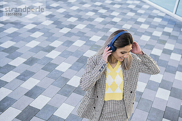 Smiling businesswoman enjoying music through wireless headphones
