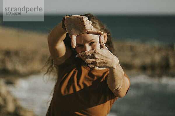 Frau macht Fingerrahmen am Strand