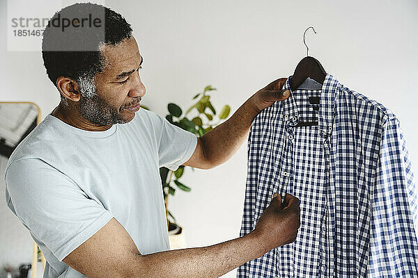 Mature man looking at checked shirt