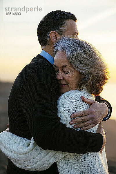 Glückliches älteres Paar  das sich am Strand umarmt