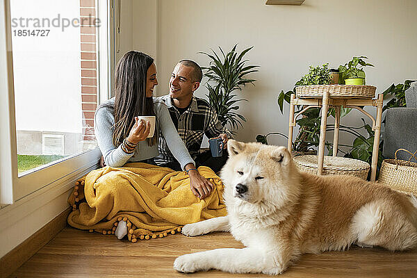 Happy couple having coffee with dog sitting in foreground