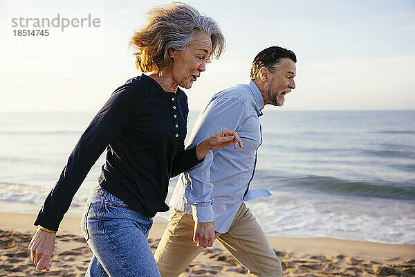 Aktiver Mann und Frau laufen am Strand