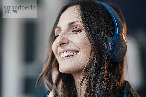 Glückliche Frau mit kabellosen Kopfhörern  die Musik hört