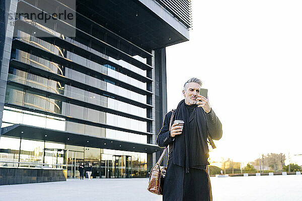 Geschäftsmann benutzt Smartphone bei Sonnenuntergang