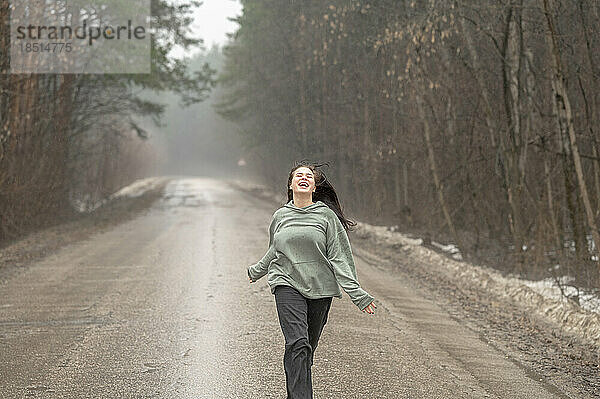 Carefree girl running on wet road