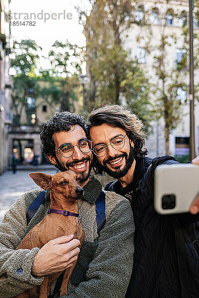 Smiling gay couple taking selfie with dog
