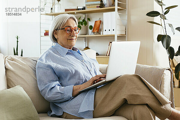Ältere Frau mit Brille und Laptop zu Hause