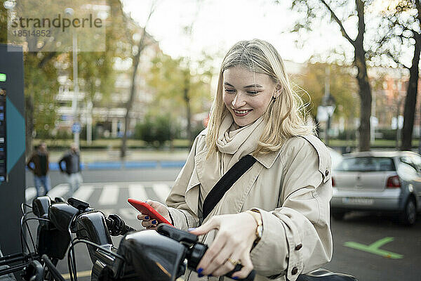 Lächelnde Frau mietet Elektrofahrrad am Parkplatz