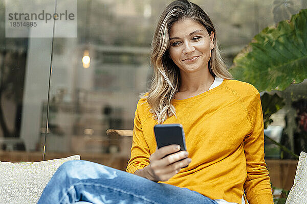 Lächelnde Frau benutzt Smartphone im Café