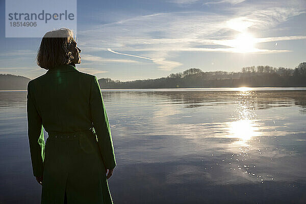 Nachdenkliche Frau blickt an einem sonnigen Tag auf den See