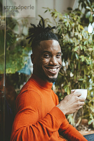 Glücklicher junger Mann mit Kaffeetasse