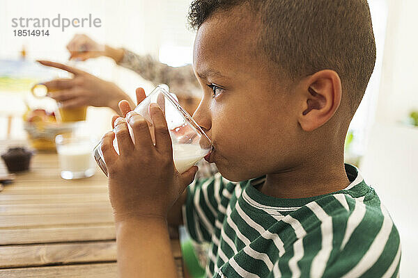 Boy drinking milk in glass at home