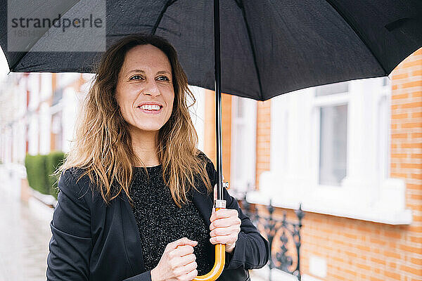 Glückliche Frau mit schwarzem Regenschirm