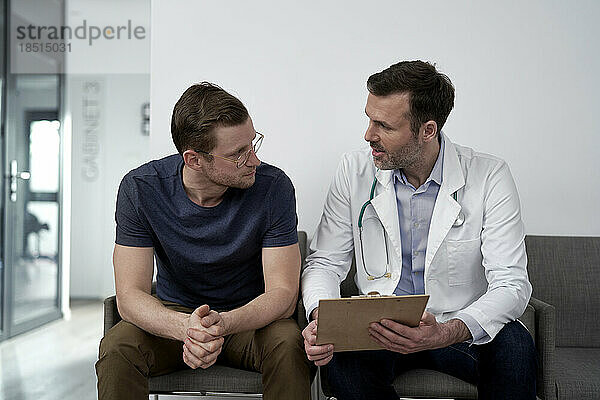 Reifer Arzt diskutiert mit Mann in der Klinik