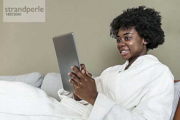 Lächelnde junge Frau  die zu Hause einen Tablet-PC benutzt