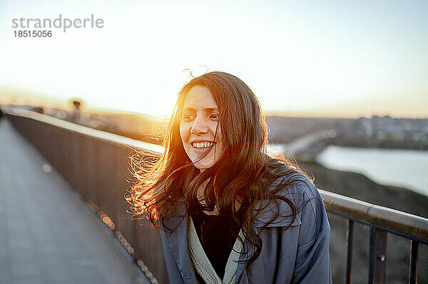 Glückliche Frau genießt den Sonnenuntergang auf der Brücke