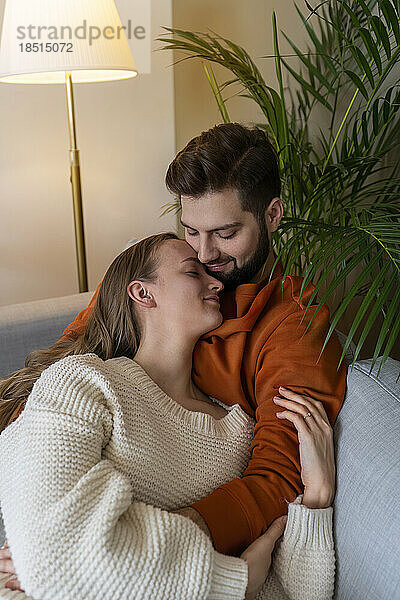 Mann umarmt Frau auf Sofa zu Hause
