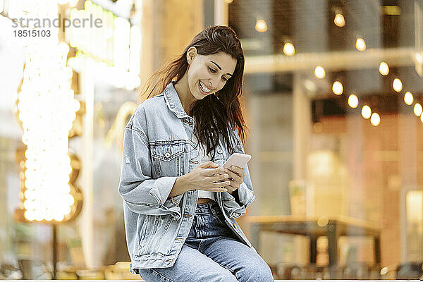 Glückliche junge Frau  die ihr Smartphone benutzt