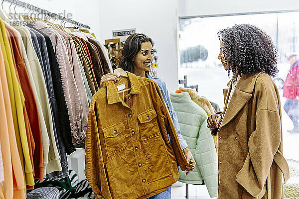 Glückliche junge Frau mit Freundin beim Einkaufen im Bekleidungsgeschäft