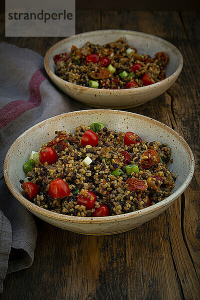 Two bowls of Beluga lentils with bulgur  tomatoes  peppers  eggplant and scallion