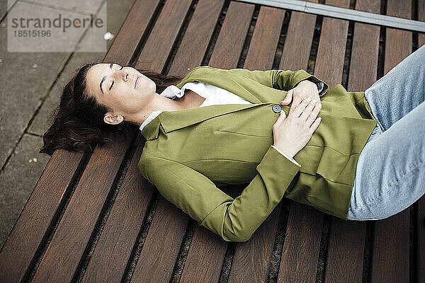Tired businesswoman lying on bench