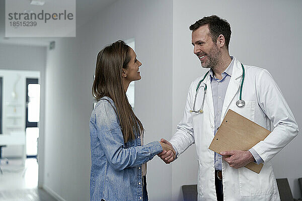 Reifer Arzt schüttelt dem Patienten in der Klinik die Hand