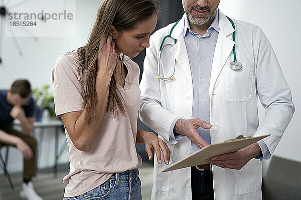 Reifer Arzt bespricht das Dokument mit dem Patienten