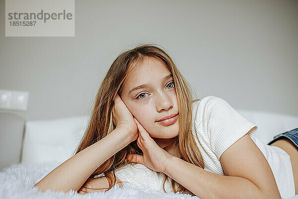 Mädchen mit blonden Haaren liegt zu Hause im Bett