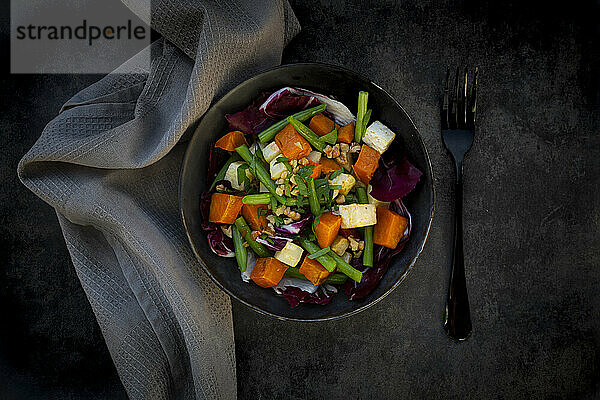 Schüssel mit verzehrfertigem vegetarischem Salat mit Süßkartoffel  Sellerie  Radicchio  grünen Bohnen  Croutons  Walnüssen und Petersilie