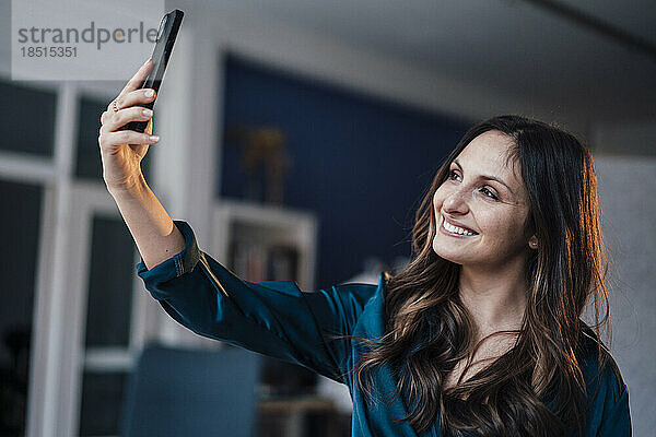 Happy young woman taking selfie at home