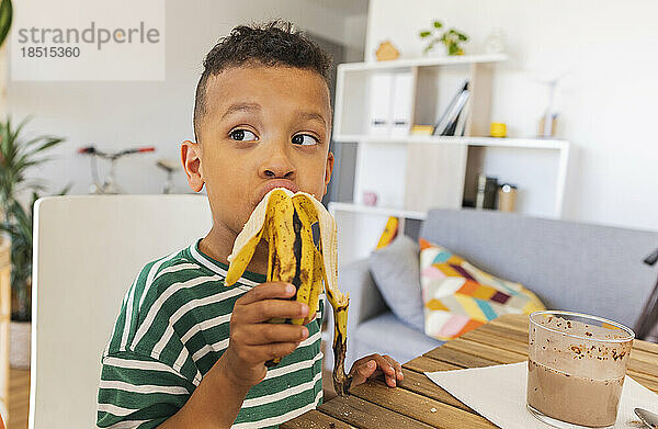 Nachdenklicher Junge  der zu Hause Banane isst