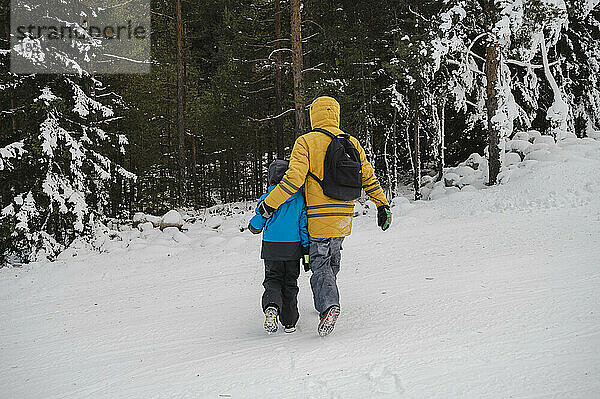 Vater geht mit Arm um Sohn im Schnee