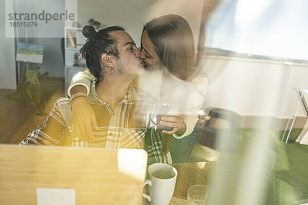 Romantic couple kissing on mouth seen through glass