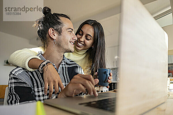 Happy woman with arm around boyfriend at home office