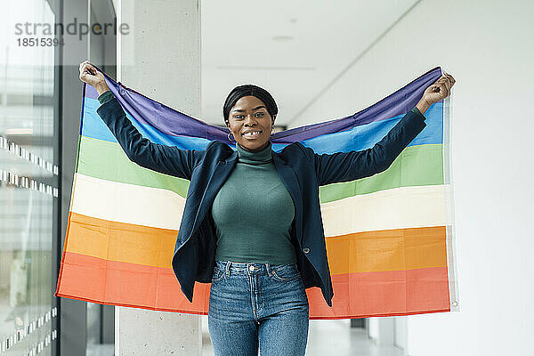 Lächelnde Geschäftsfrau mit Regenbogenfahne im Büro