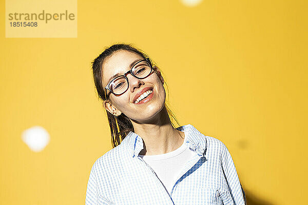 Happy young woman wearing eyeglasses against colored background