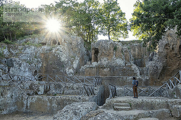 Mann mit Rucksack blickt auf das steinerne Tempelgrab  Toskana  Italien