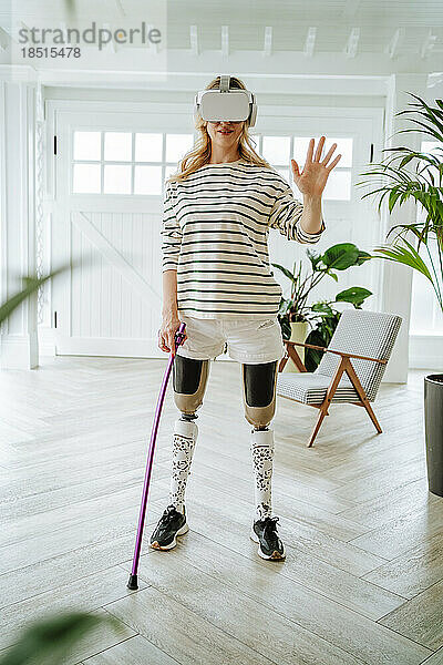 Frau mit Beinprothese spielt zu Hause Spiele über eine VR-Brille