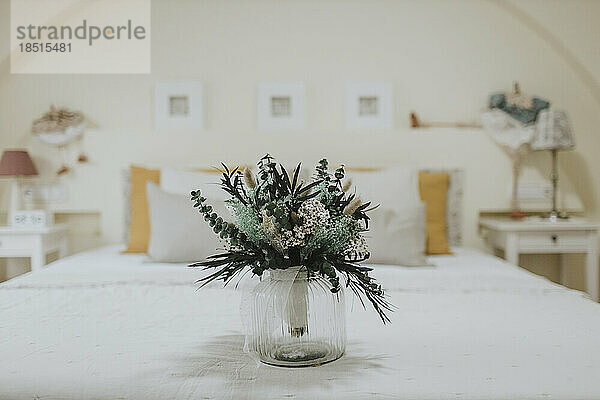 Bridal bouquet in vase on bed