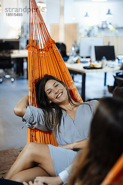 Smiling businesswoman with colleague relaxing in hammock