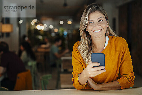 Glückliche Frau mit Handy im Café