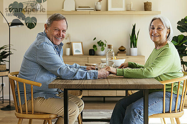 Glückliches Paar hält Händchen am Tisch zu Hause