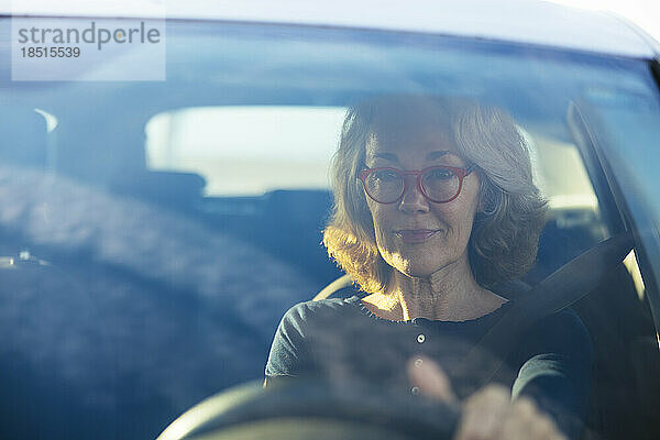 Frau mit Brille beim Autofahren durch Windschutzscheibe gesehen