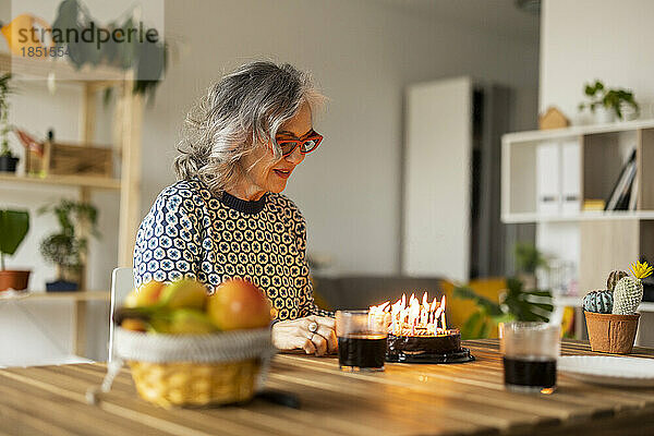 Lächelnde reife Frau  die zu Hause Geburtstag feiert