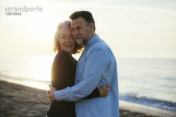Mature man hugging woman at sunrise