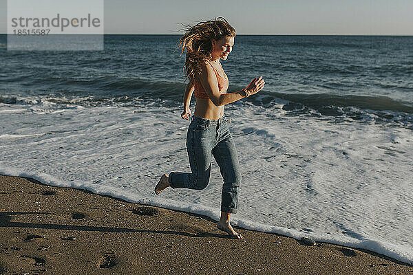 Glückliche Frau läuft und genießt am Strand