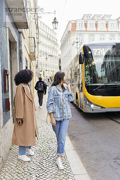 Junge Frau mit Freundin blickt auf Bus
