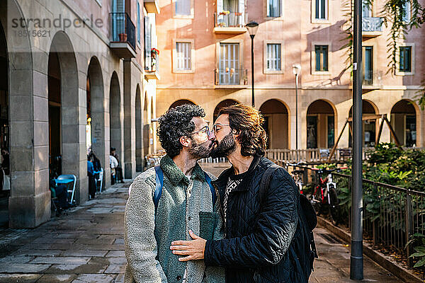 Liebevolles schwules Paar  das sich auf dem Fußweg küsst