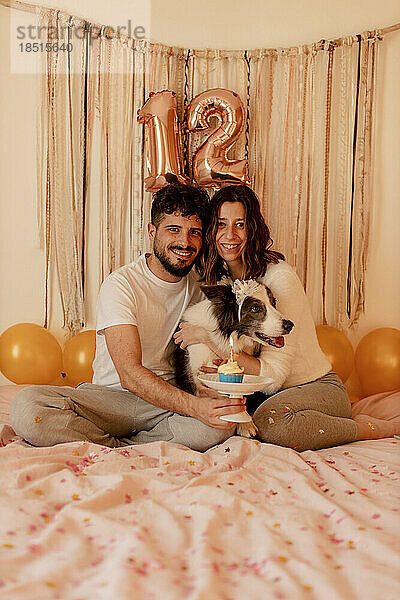 Glückliche Männer und Frauen feiern zu Hause den Geburtstag des Border-Collie-Hundes